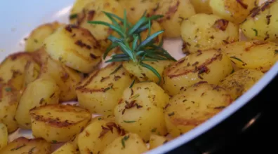 fondant potatoes in a dish with a sprig of rosemary