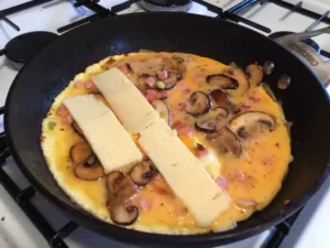 Bacon, mushroom and cheese omelette preparation